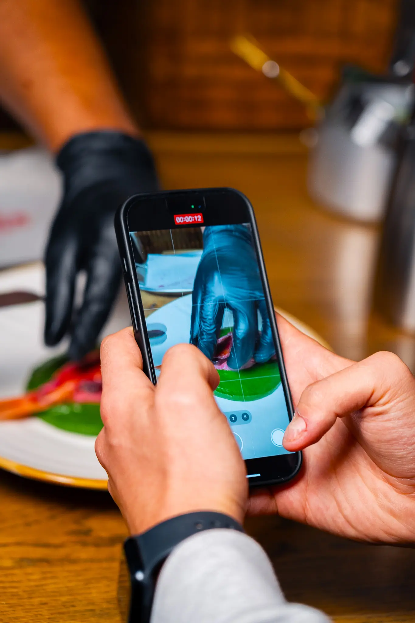 Ripresa con lo smartphone di uno chef che impiatta con i guanti