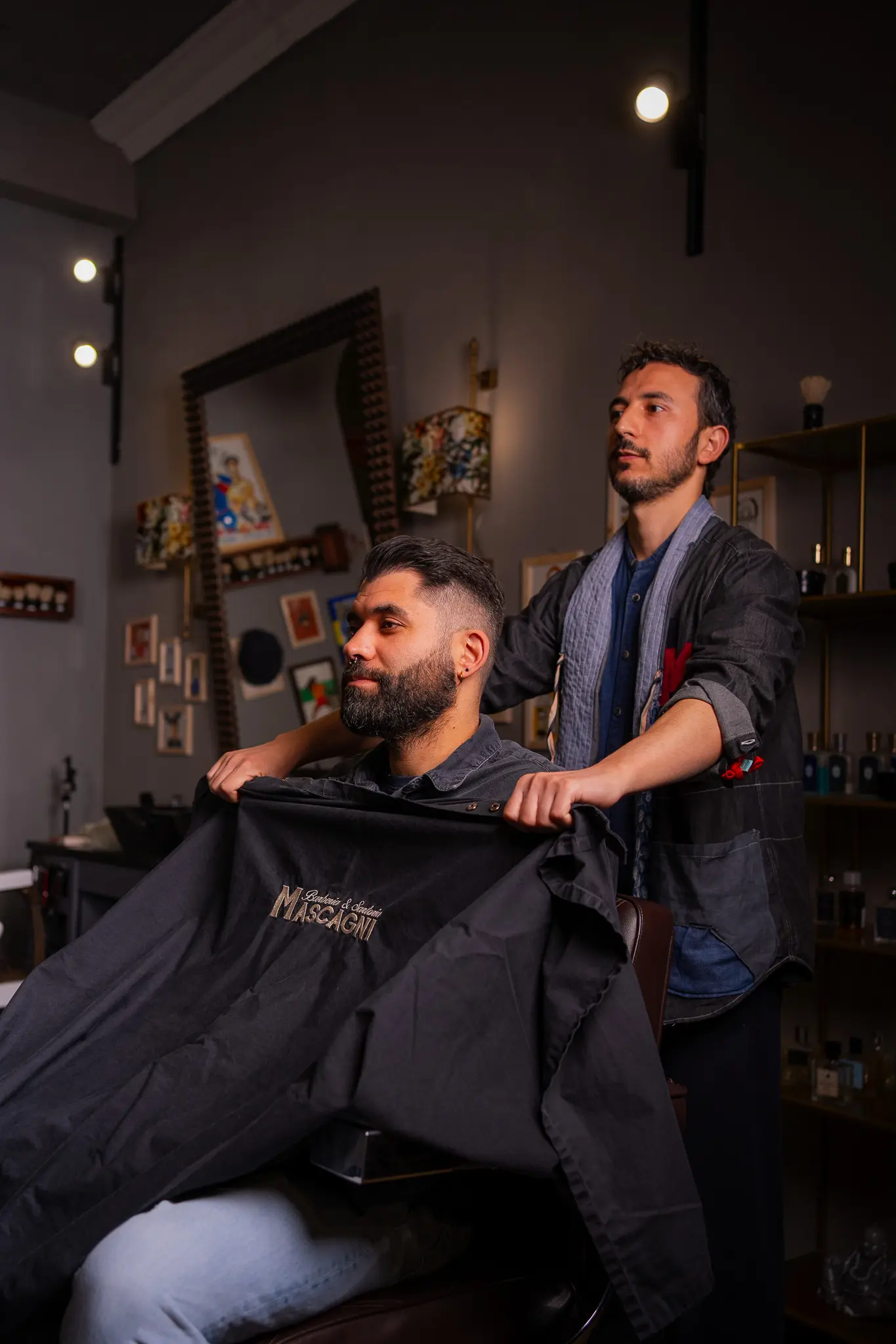 Barbiere e cliente davanti allo specchio in una bottega dai toni scuri