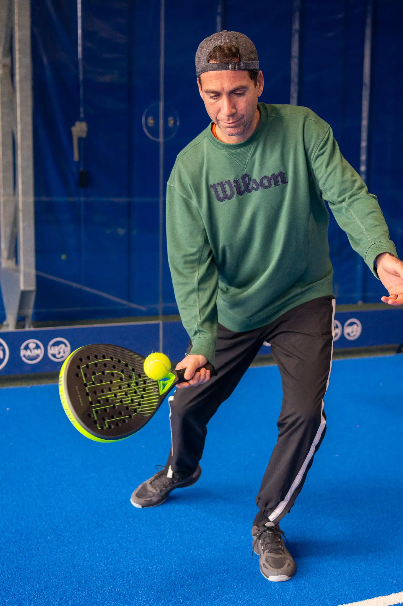 Giocatore di padel che colpisce la palla sul campo blu